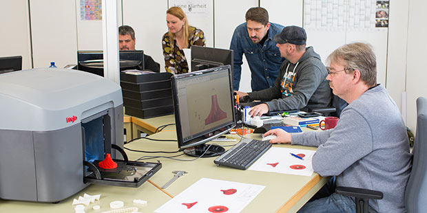 Eine Personengruppe arbeitet vor Computerbildschirmen an einem Ausbildungsprojekt