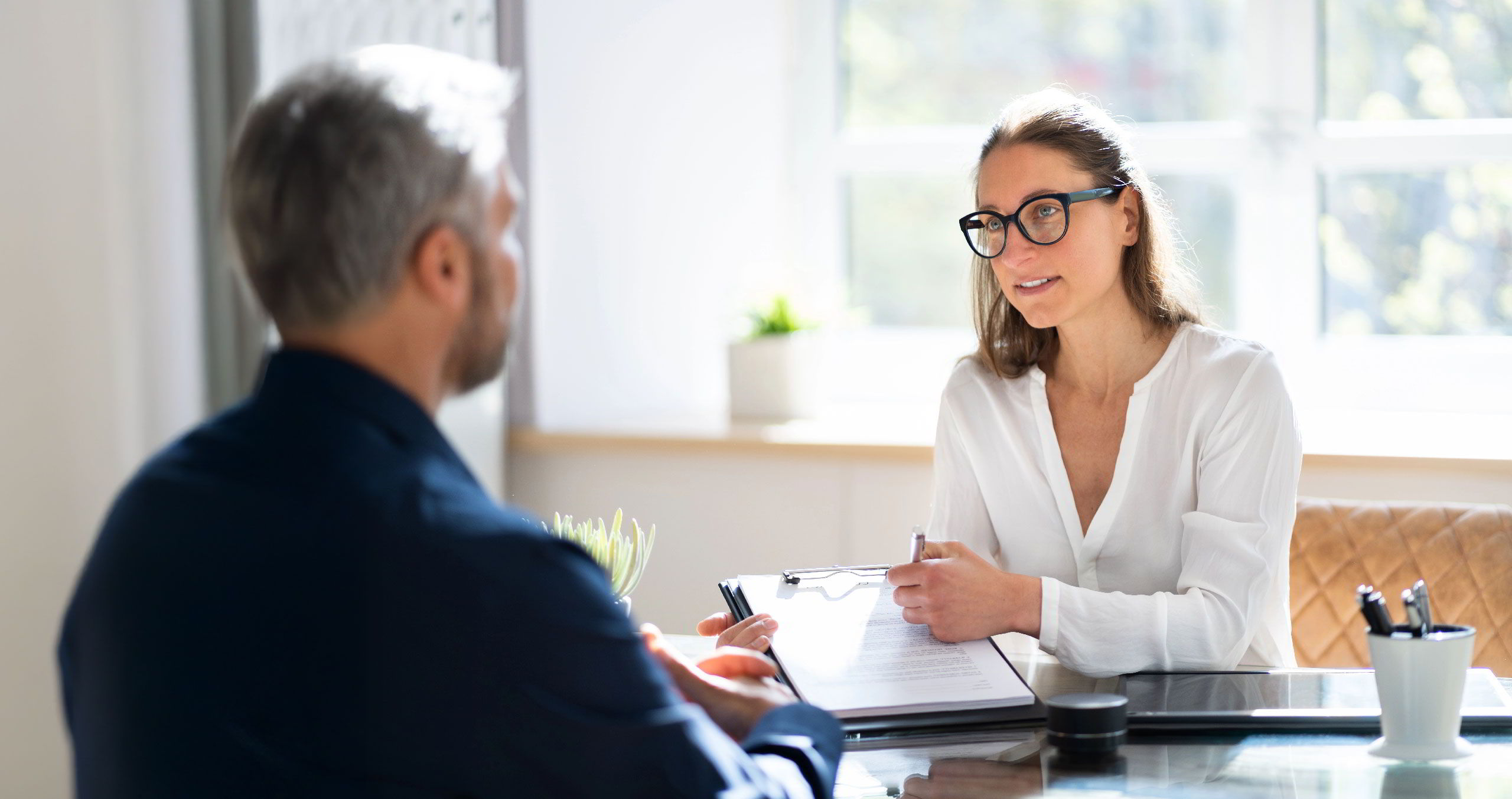 Foto einer Mitarbeiterin während eines Beratungsgespräches mit einem Mann.