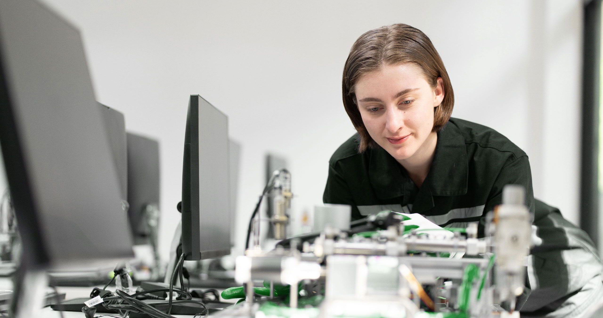 Foto in einem Computerraum. Eine junge Teilnehmerin betrachtet technische Bauteile.