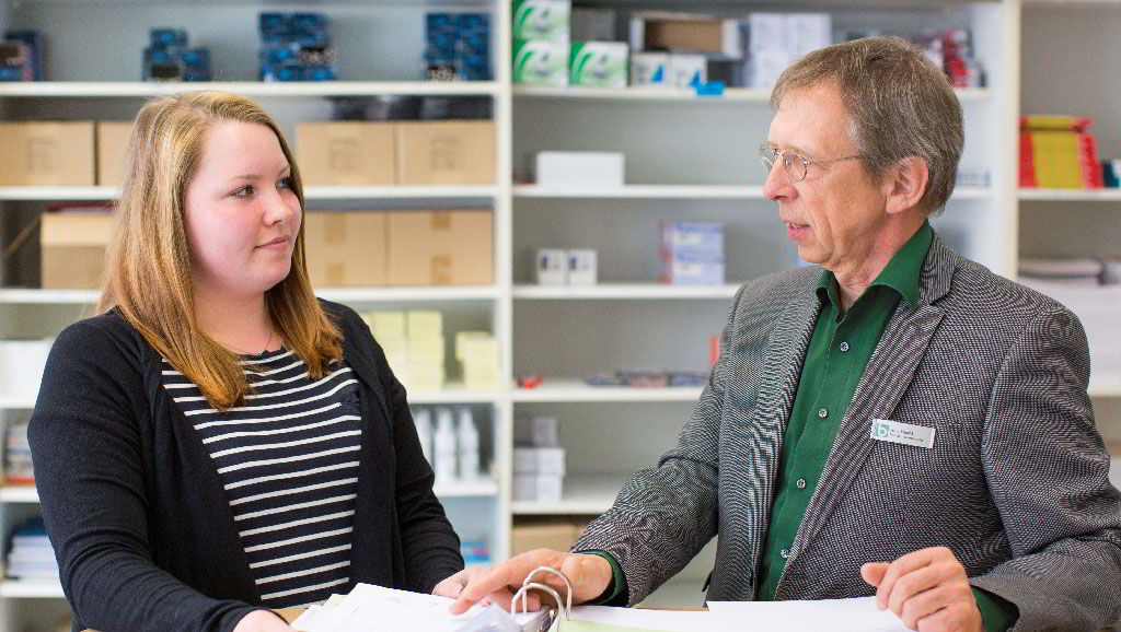 Ein Mitarbeiter des BFW-Frankfurt in grauem Jacket an einem Stehtisch im Gespräch mit einer jungen Frau